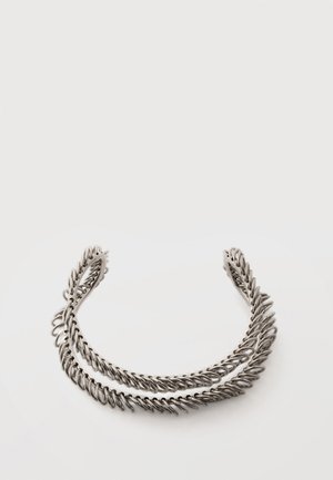 Ασημένιο βραχιόλι με σχήμα μανσέτας από στριφογυριστό μέταλλο με περίπλοκο σχέδιο που θυμίζει φύλλα, σχέδιο με ανοιχτά άκρα, εμφανίζεται σε λευκό φόντο.