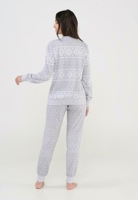 Conjunto de pijama gris con un patrón de copos de nieve en la parte superior, de manga larga, y pantalones a juego con un diseño de lunares, ambos en una tela suave.