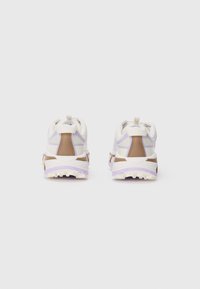 Des chaussures de course blanches et brunes avec un design en maille, une semelle en caoutchouc texturée et des accents violets sur le semelle intermédiaire et la zone du talon.