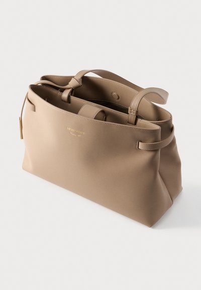 Μπεζ τσάντα tote από λείο συνθετικό υλικό, με δύο επάνω λαβές, ευρύχωρο εσωτερικό και διακριτική λεπτομέρεια λογότυπου μπροστά.