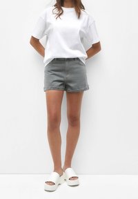 Gray denim shorts with rolled hem, paired with a plain white cotton t-shirt and white platform sandals. Minimalistic style.