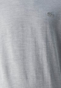 T-shirt gris en tissu doux et lisse. Présente un petit logo brodé sur la poitrine gauche. Design simple et classique avec un col rond.