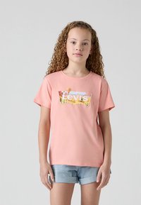 Rózsaszín pamut póló fehér Levi's logóval és színes grafikus háttérrel. Kerek nyakkivágás és rövid ujjú. Laza szabású, hétköznapi viselet.