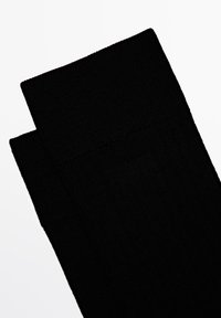 Czarne skarpetki ribbed z teksturowanym splotem i grubym mankietem, prezentujące jednolity kolor i gładkie wykończenie.