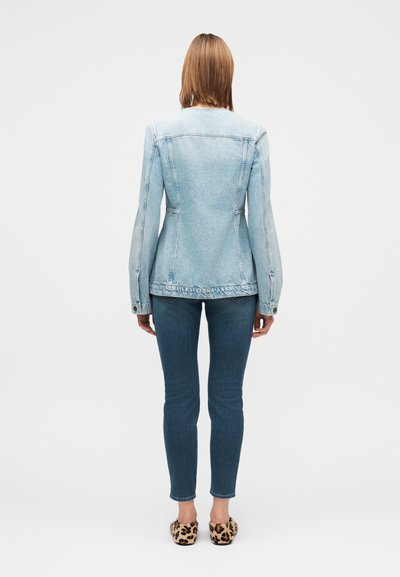 Veste en jean bleu clair à la coupe ajustée, coutures apparentes et boutons en guise d'accents, associée à un jean skinny foncé et des ballerines à imprimé léopard.