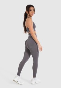 Grijze sportbeha en legging set, met een strakke pasvorm, zachte textuur, halternekontwerp en hoge taille. Geaccentueerd met logo banden.