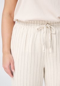 Helle beige Leinenhose mit vertikalen dunkelblauen Streifen, ausgestattet mit einem elastischen Taillenbund und einer verstellbaren Krawatte auf der Vorderseite.