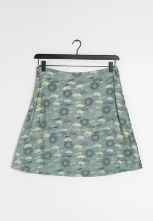 Jupe trapèze en bleu sarcelle atténué avec des motifs de soleil, lune et nuage en jaune, blanc et gris, suspendue à un cintre noir.