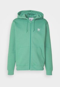 Felpa verde con zip, realizzata in tessuto morbido, dotata di tasca a marsupio, cappuccio regolabile con cordino e logo Adidas bianco sul petto.
