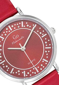 Montre-bracelet en quartz rouge avec un boîtier métallique rond, des index horaires blancs, des accents en point et un bracelet en cuir rouge assorti.