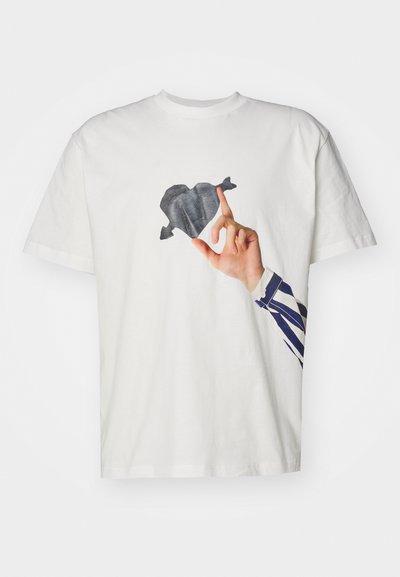 Tricou alb din bumbac, cu un imprimeu al unei mâini ce are o formă de inimă neagră, completat de un braț cu un design în dungi albastre și albe.