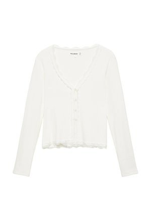 Cardigan court blanc à manches longues avec bords festonnés, boutons sur le devant et une bordure texturée le long de l'encolure et de l'ourlet.