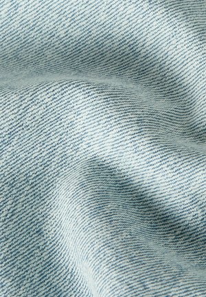 Light blue denim fabric with visible diagonal weave pattern and soft folds creating shadowed texture.