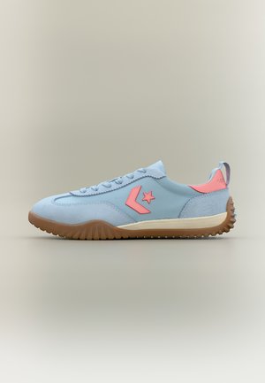 Hellblauer Sneaker mit pinkem Stern-Logo, brauner Gummisohle, Schnürverschluss vorne und Fersenlasche, auf neutralem Hintergrund dargestellt, Seitenprofilansicht.