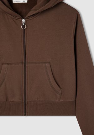 Brązowa bluza z zamkiem błyskawicznym i kieszeniami z przodu, z prążkowanym dołem oraz metalowym uchwytem do zamka, prezentująca się na jasnym jednolitym tle.