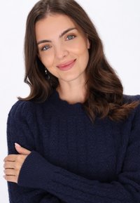 Marineblauer, gestrickter Pullover mit einem strukturierten Muster, gerippten Bündchen und einem weiten Ausschnitt. Das Material wirkt weich und gemütlich.