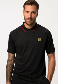 Polo nero con accenti rossi sul colletto. Presenta righe verticali e un logo dorato sul petto. Tessuto morbido e liscio. Maniche corte.