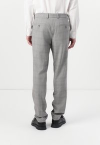 Pantaloni grigi a quadri con vestibilità slim, caratterizzati da un frontale piatto, due tasche posteriori e un tessuto leggero. Indossati con scarpe nere.