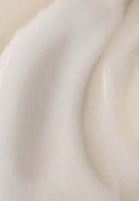 Biała ceramiczna miska o gładkich kształtach, z błyszczącym wykończeniem i subtelną fakturą powierzchni, na tle miękkiego, beżowego koloru.