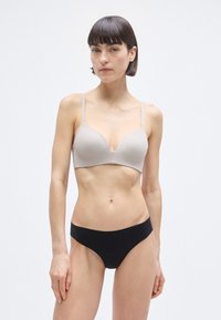 Ανοιχτό γκρι επενδεδυμένο σουτιέν με λεπτές τιράντες και V-σχήμα στο ντεκολτέ. Μαύρο σλιπ χωρίς ραφές με χαμηλή μέση που κάθεται στα ισχία.