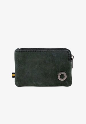 Cartera de ante verde con cremallera, con un logo circular plateado y un acento a rayas en negro y amarillo. Textura suave y forma rectangular.