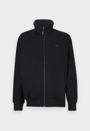 Czarna kurtka na zamek z wysokim kołnierzem, ściągaczami na mankietach i dole, z trzema pionowymi paskami na rękawach oraz logo na piersi.