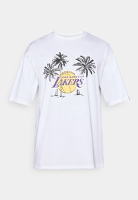 Biely bavlnený tričko s fialovým logom "Los Angeles Lakers", grafikou paliem a ilustráciou pozadia basketbalu.