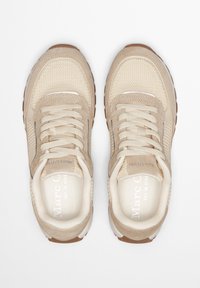 Baskets beige en mesh et daim, avec une tige texturée, des lacets plats et une semelle en caoutchouc marron. Marque visible sur la semelle intérieure.