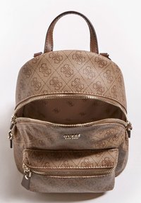 Pieni ruskea kuvioitu Guess-reppu, jossa on kaksi vetoketjullista osastoa ja yläkahva valkoista taustaa vasten.