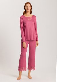 Rosa loungemössa med långärmad topp med spetsklänning och matchande byxor med spetskant vid nederkanten. Slätt tyg, avslappnad passform.
