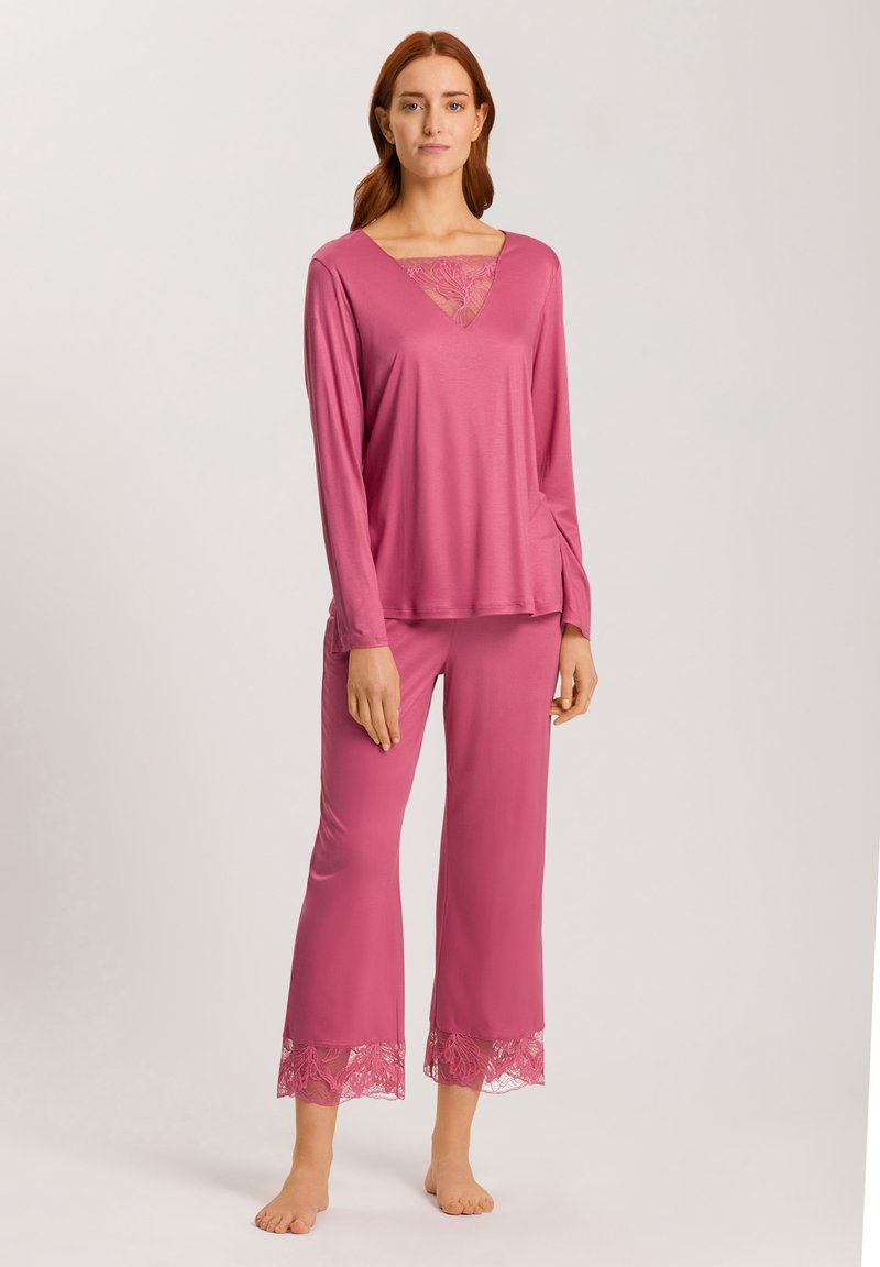 Rosa loungemössa med långärmad topp med spetsklänning och matchande byxor med spetskant vid nederkanten. Slätt tyg, avslappnad passform.
