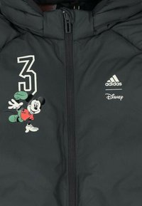 Giacca nera trapuntata con chiusura a zip, caratterizzata da testo bianco "3," un grafico di Mickey Mouse della Disney e il logo Adidas in bianco.