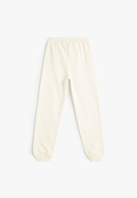 Pantalons de survêtement couleur crème clair fabriqués en tissu doux, dotés d'une taille élastique et de poignets fuselés. Design simple et sans couture.