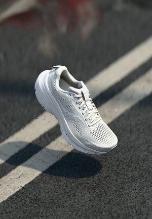 Weißer Laufschuh mit einem Obermaterial aus Mesh, abgerundetem Zehenbereich, gepolsterter Sohle und Schnürsenkeln. Er verfügt über Belüftungslöcher und ein schlankes Design.