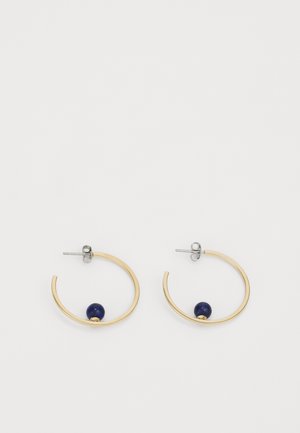 Gouden open oorringen met kleine donkerblauwe kralen aan de onderkant in het midden van elke ring en zilveren stekers.