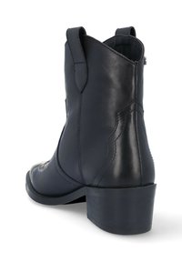 Botín negro de cuero a la altura del tobillo con punta cuadrada, lengüeta, y un tacón bajo y robusto. Textura suave con sutiles detalles de costura en los laterales.