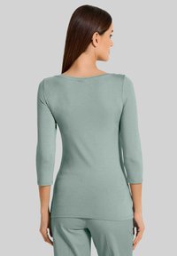 Mintgroene, getailleerde shirt met lange mouwen en een bootnek in driekwartmouwen. Gladde textuur, casual ontwerp, met een rechte zoom.