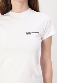 Witte katoenen T-shirt met een ronde hals en korte mouwen. Op de voorkant staat een zwart logo met de tekst "KARL LAGERFELD JEANS."