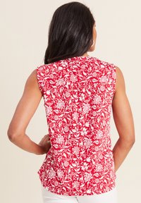 Blusa senza maniche a fantasia floreale rossa realizzata in tessuto leggero, con disegni botanici bianchi e vestibilità rilassata. Dettagli sul retro visibili.