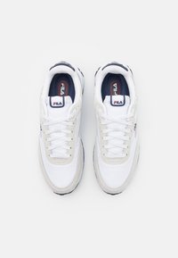 Scarpe da ginnastica bianche con parte superiore in rete, design con lacci, accenti grigi e un logo sulla linguetta. Suola spessa in gomma con battistrada testurizzato.