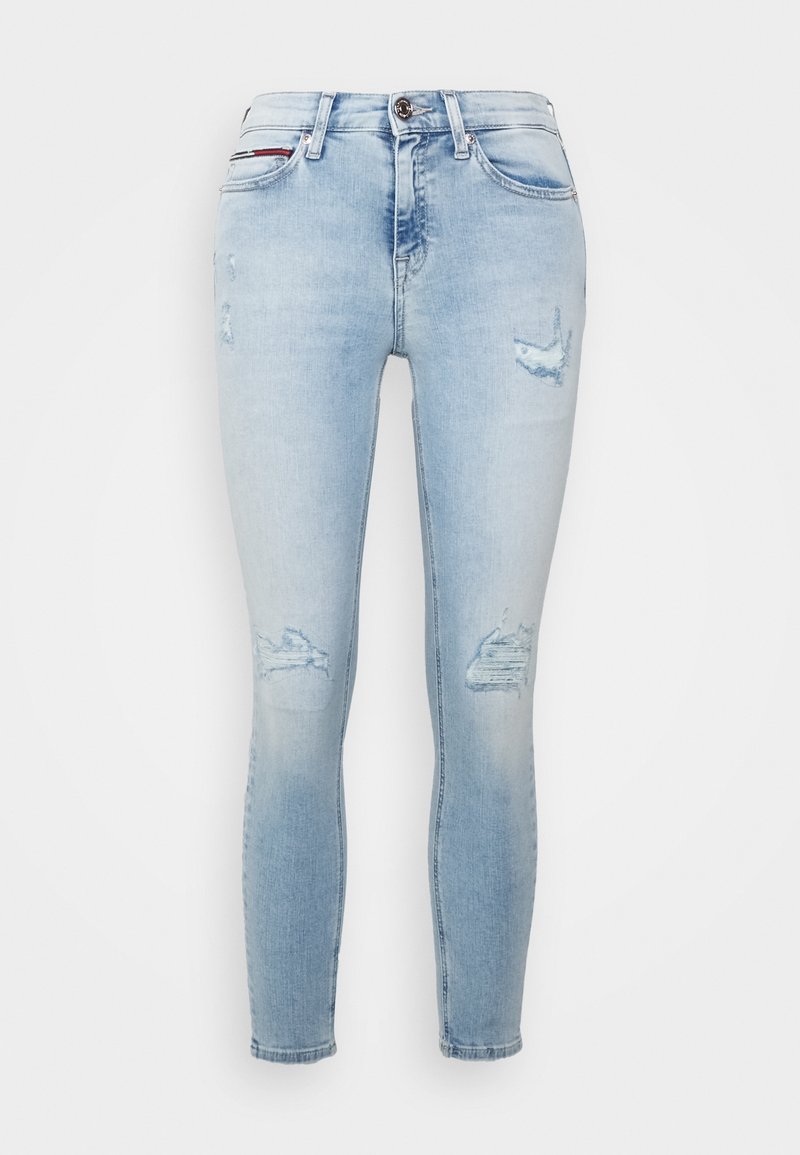 Jeans ajustados de color azul claro con parches desgastados en los muslos y las rodillas, estilo de cinco bolsillos y cierre de botón en la cintura.