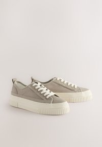 Grijze canvas sneakers met witte veters en een gestructureerde rubberen zool. Voorzien van een afgeronde neus en een trekkoordje aan de hiel voor gemakkelijk aantrekken.