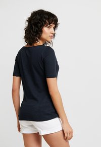 Marineblå kortermet t-skjorte i et mykt, lett stoff med rund hals og en tettsittende fasong, stylet med hvite shorts.