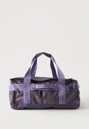 Borsone rettangolare viola con doppie maniglie, chiusura superiore con zip e clip laterali, appoggiato su una superficie bianca.