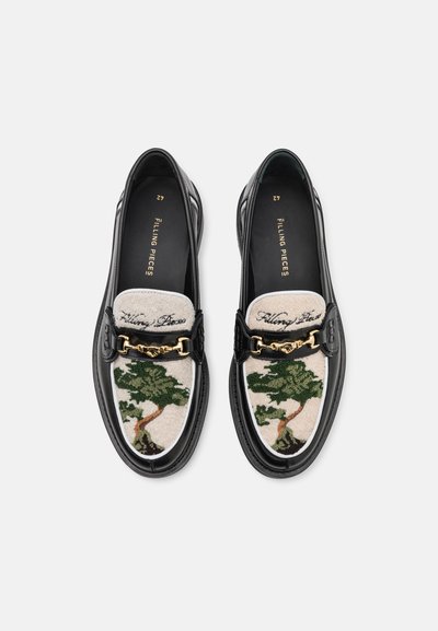 Musta nahka loaferit, joissa on brodeeratun puu-kuvio cream-kankaalla, kultaketju-yksityiskohta ja kontrastivaalea musta pohja lisätekstuurin vuoksi.