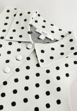 Weißes Poloshirt mit schwarzen Punkten, versehen mit einem Kragen und drei passenden Knöpfen. Weiche Strickstruktur, Markenetikett sichtbar.