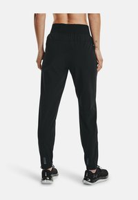 Pantalones deportivos negros con cintura elástica, diseño de pierna ajustada y acentos reflectantes cerca de los tobillos. Fabricados con material liviano.