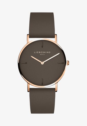 Brunt læderrem ur med en rund mørkebrun skive, guldfarvede visere og minimalistisk design. Mærket "LIEBESKIND BERLIN" vises.