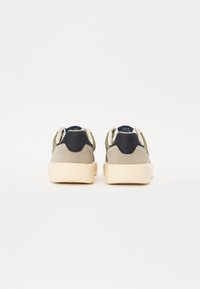 Suede sneakers i grønn, grå og marineblå, med en kremfarget såle. Har en rund tå og polstret krage for komfort.