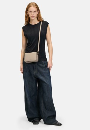 Schwarzes, geripptes, ärmelloses Top, locker sitzende, dunkelblaue Jeanshose und eine hellbeige Umhängetasche mit glatter Textur.